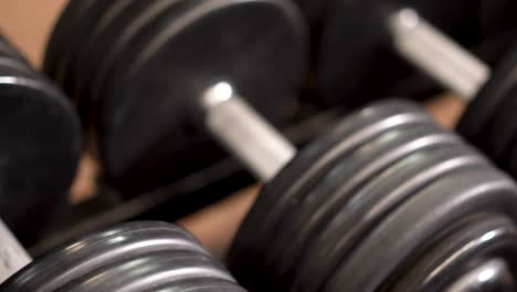 extreme closeup, slow slider shot to the left looking down on row of dumbbells on a rack