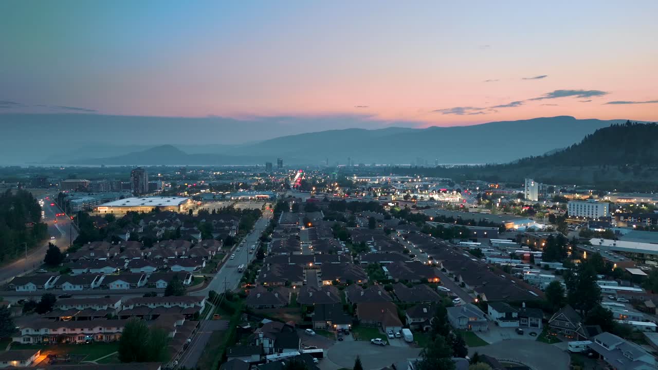 Admire the Kelowna city skyline at dusk, with stunning aerial views of Okanagan Valley’s urban beauty, highlighted by the warm glow of the sunset.