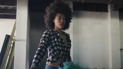 Mixed-race-woman-holding-green-flare-standing-in-an-empty-building