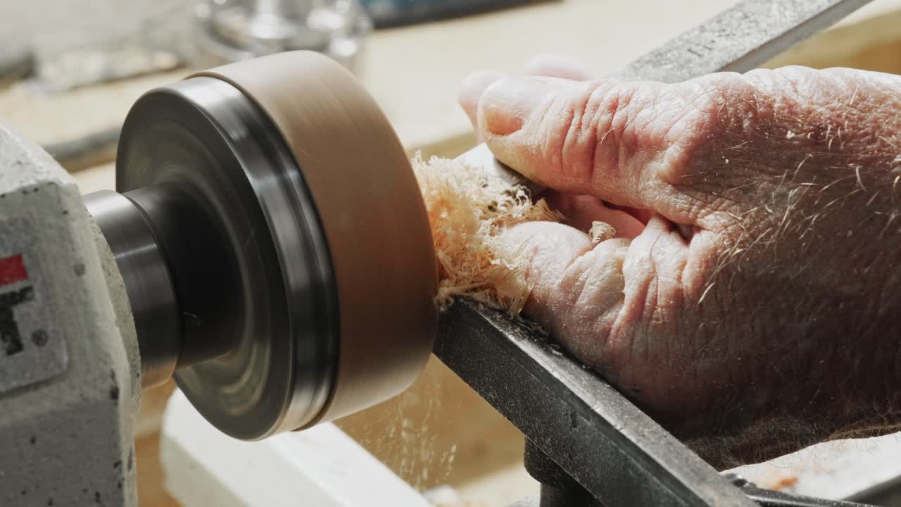 старик с помощью токарного станка и резца, чтобы поворачивать и резать деревянный диск