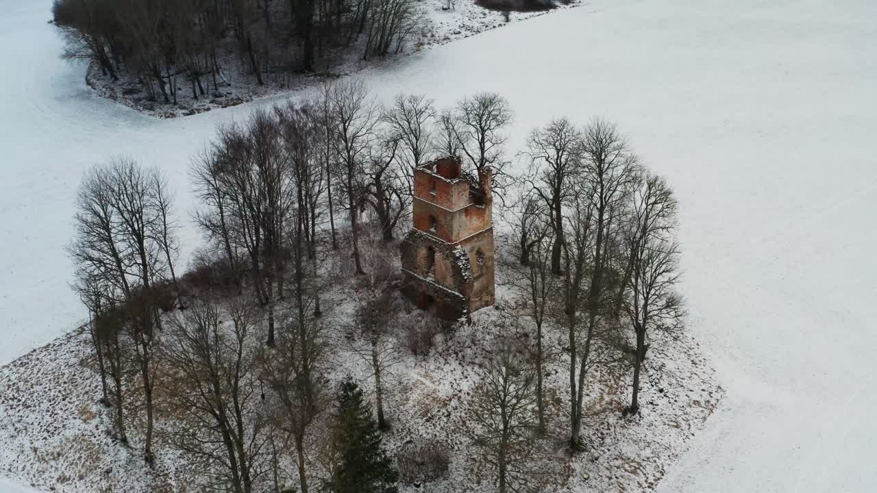 vista aérea de las ruinas de la antigua torre de la iglesia entre los árboles durante el invierno nevado
