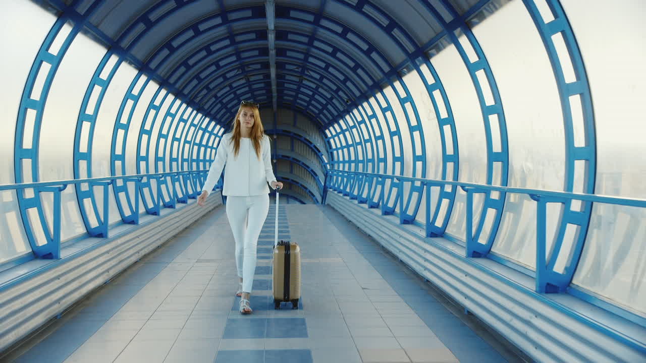 joven empresaria con bolsa de viaje sobre ruedas está en transición desde la terminal del aeropuerto