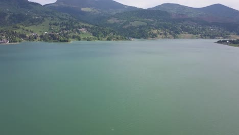 toma panorámica aérea hacia arriba del lago con montañas en el fondo en un día soleado