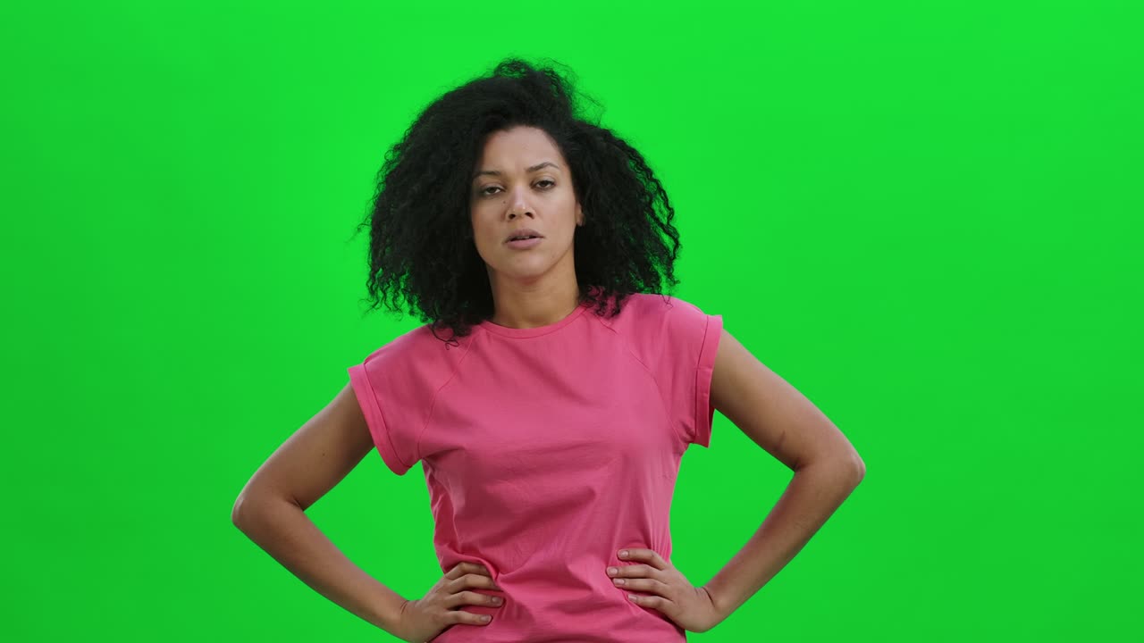 Portrait of young female African American swears and shakes viciously with his index finger. Black woman with curly hair poses on green screen in the studio. Close up. Slow motion ready 59.97fps