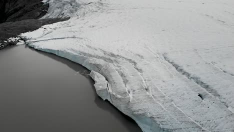 sobrevuelo aéreo con una vista aérea del lago glacial del glaciar claridenfirn en uri, suiza al anochecer con una vista panorámica giratoria hacia el cielo brillante detrás de los picos alpinos