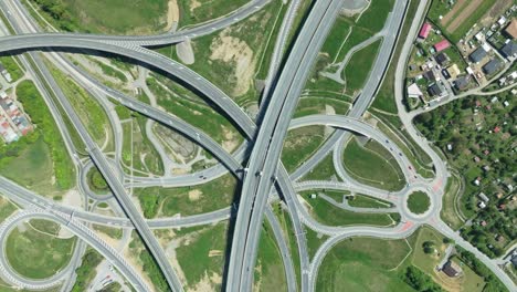 From-above,-a-drone-offers-a-zoom-in-perspective-of-a-complex-highway-junction,-where-cars-maneuver-through-intricate-roundabouts-and-intersecting-roads