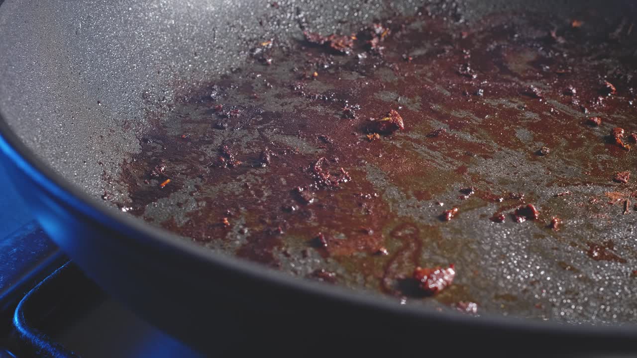 Spruzzando olio da cucina in una padella usata per friggere.