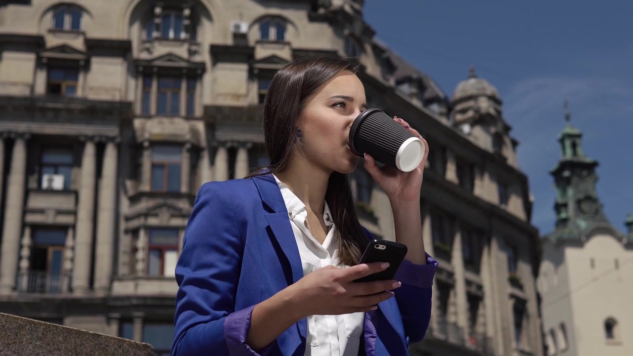 Jovem empresária usando smartphone e bebendo café ao ar livre