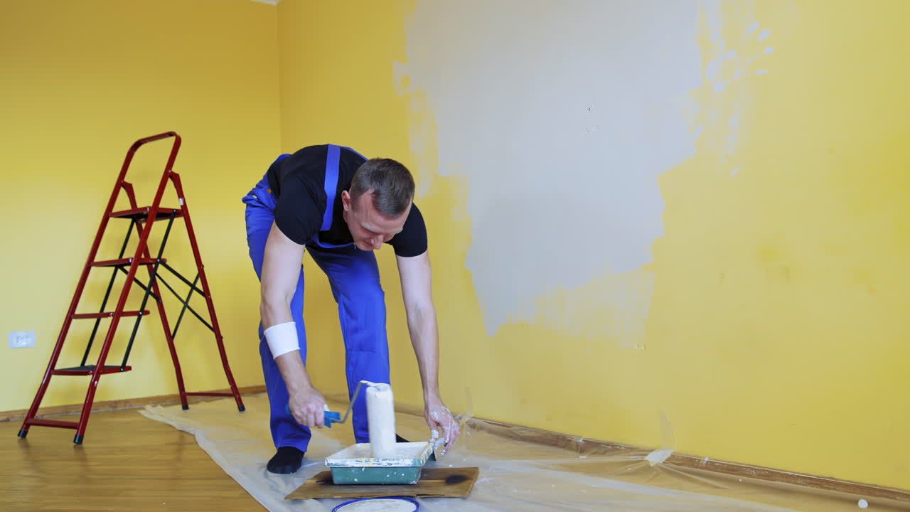 Apartment redecoration and home construction. Painting wall with roller brush by handyman during home renovation