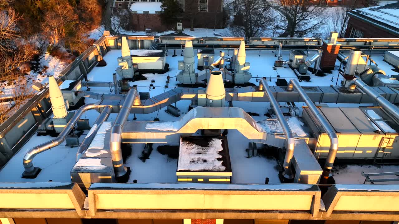 Drone footage of a rooftop HVAC system covered in snow, showcasing industrial design and structural details under soft winter lighting in Northampton