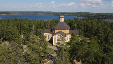 Iglesia-De-Laukaa,-Finlandia,-Toma-En-órbita-De-Un-Dron-De-La-Antigua-Iglesia-De-Madera-En-Medio-De-Lagos-Y-Bosques-En-Un-Hermoso-Día-De-Verano