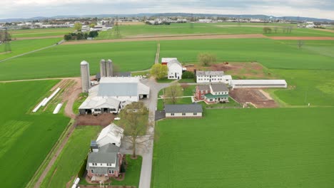 aerial tracking shot above long farm lane toward farmland fields