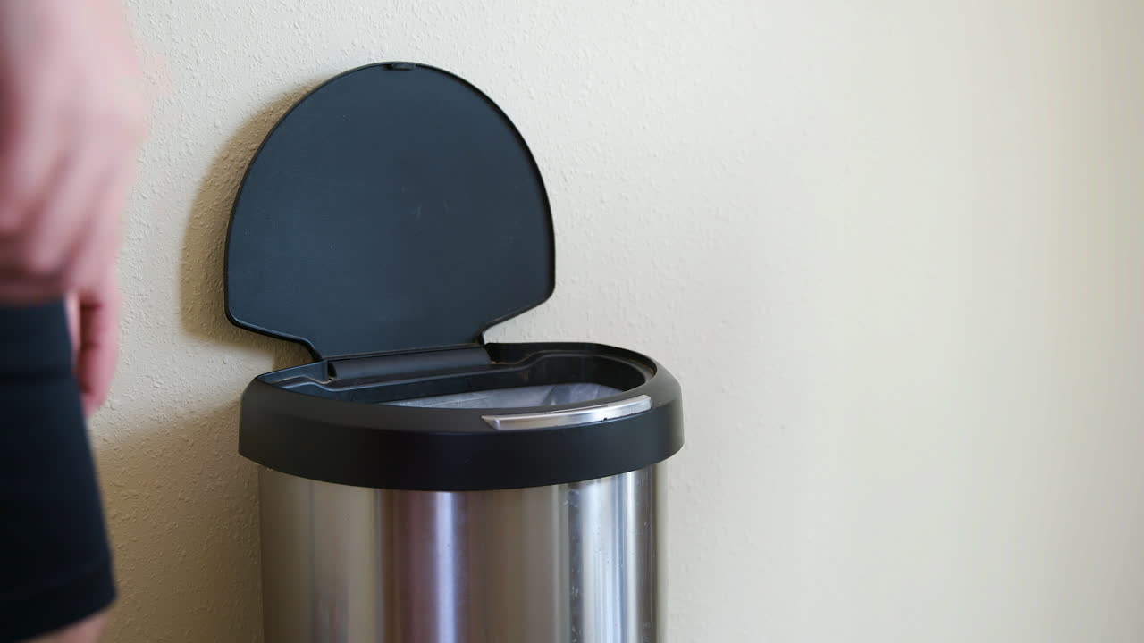 남자는 터치리스 쓰레기통을 감지하여 종이 타월을 버립니다 - 중간 쪽