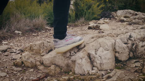 Man-with-camera-walking-on-a-rocky-mountain-trail,-lone-traveler-hike