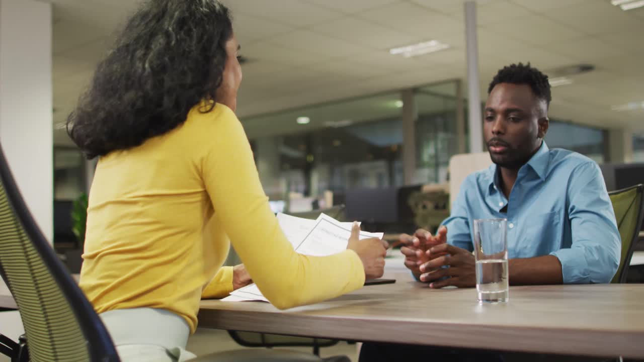 Video of happy diverse businessman and businesswoman talking about project and shaking hands