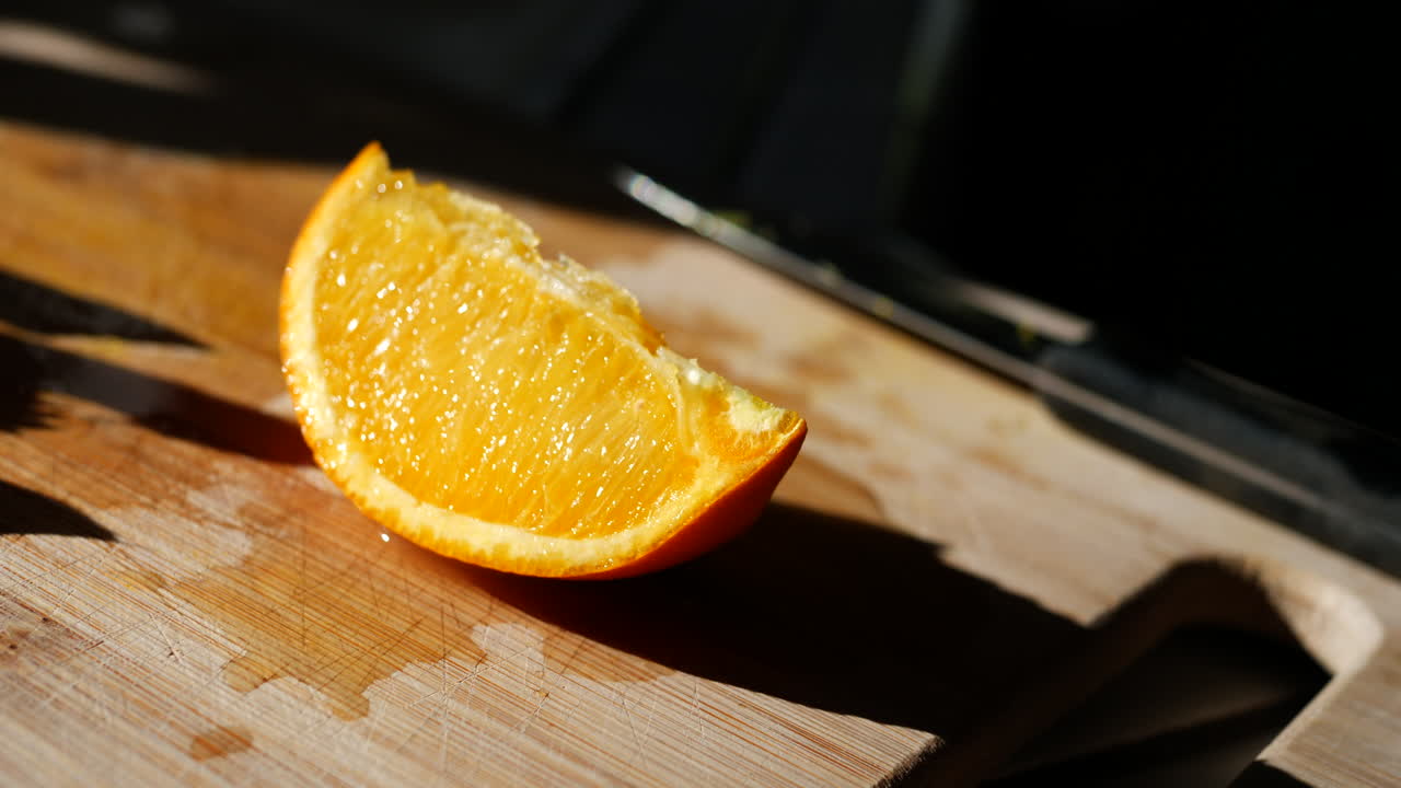 una rodaja de naranja colorida en una tabla de cortar a la luz del sol para un refrigerio saludable