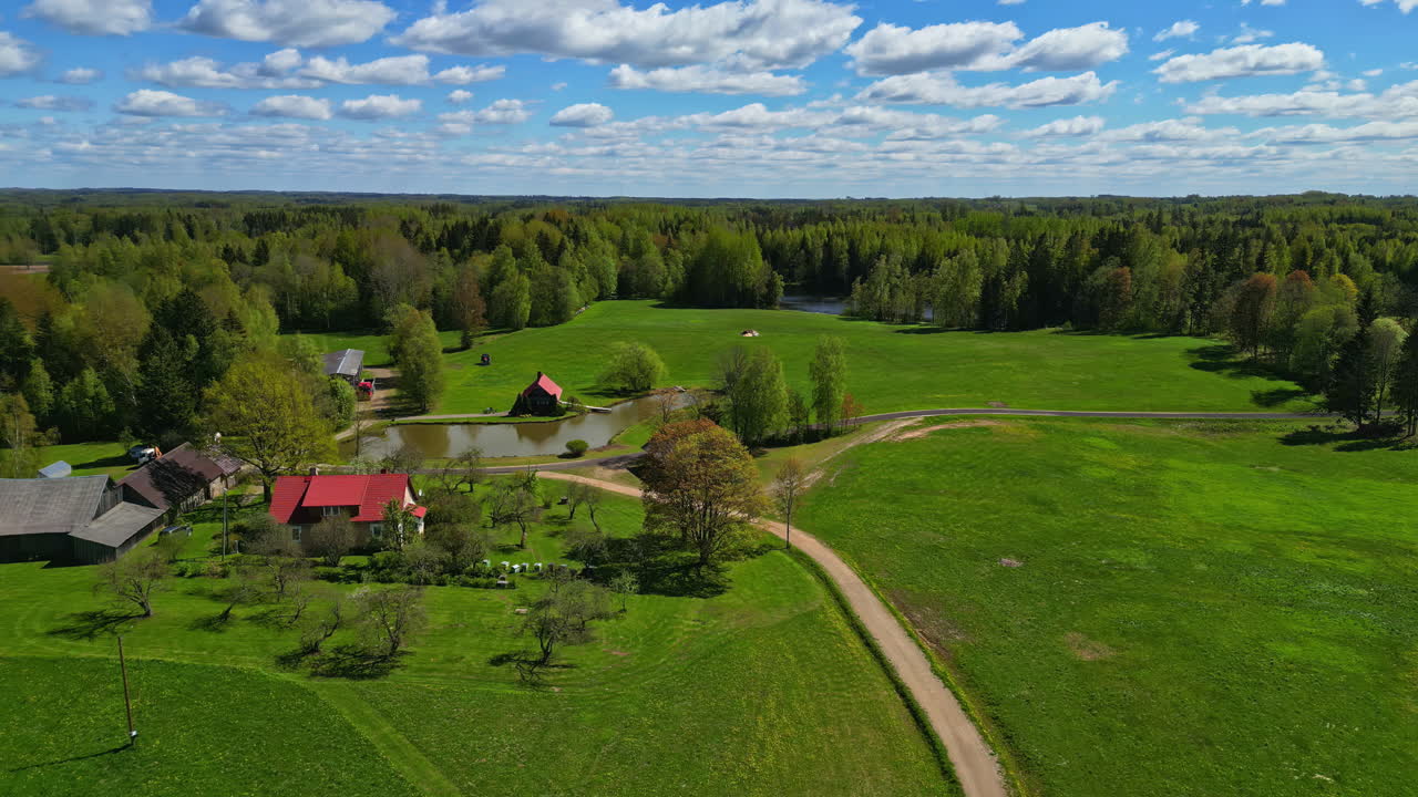 라트비아의 초록색 시골에서 은 날에 원형 연못 에 있는 은 집들의 풍경