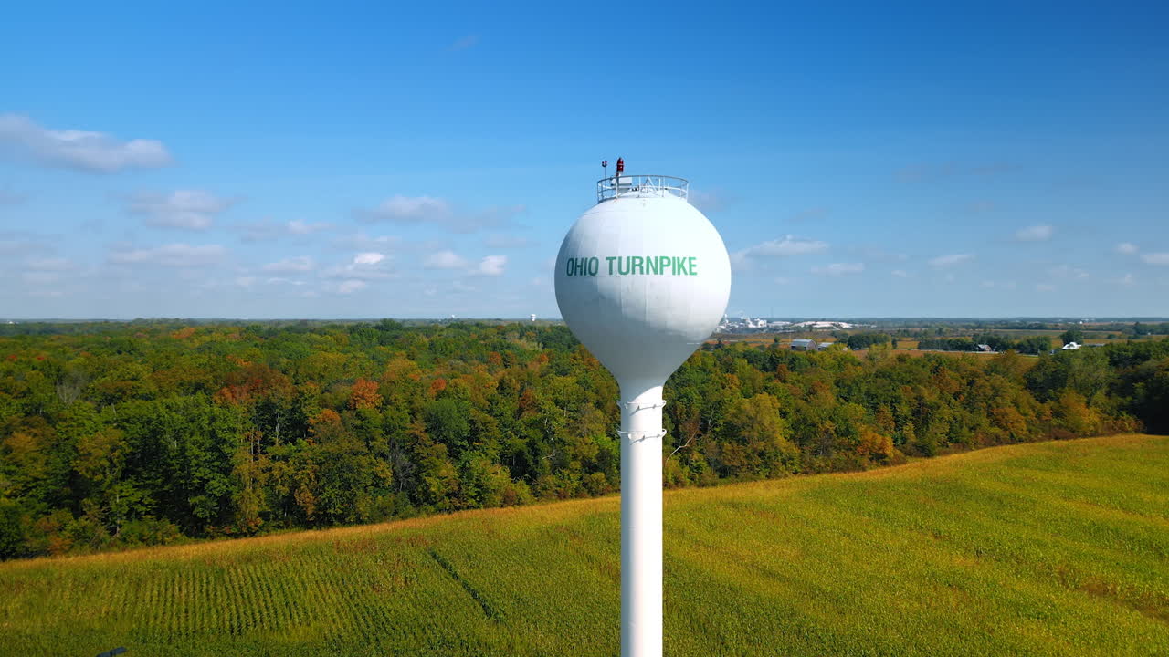 Chicago, USA, 29 June 2025: Bulb top of the water tower with a sign Ohio Turnpike. Beautiful green field and lush forests at backdrop