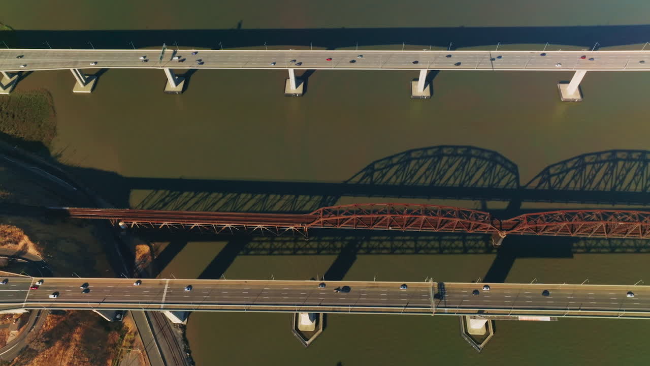 Railway bridge between automobile bridges in Martinez, California, USA. Bird's eye view on the bridges at backdrop of dark water.