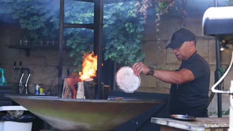 man adding wood to outdoor fire pit