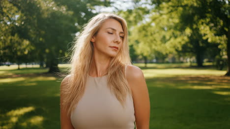 portrait of a blonde woman standing in a sunny park