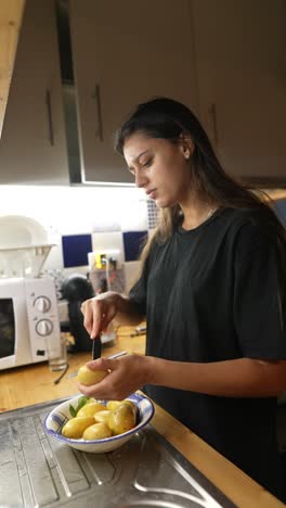 mujer pelando patatas en la cocina