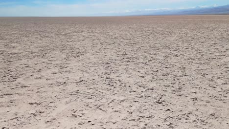 drone footage flying forward over the atacama desert salt flats during daylight. the aerial view captures salt crusts and lithium deposits, revealing the arid landscape the horizon and the mountains