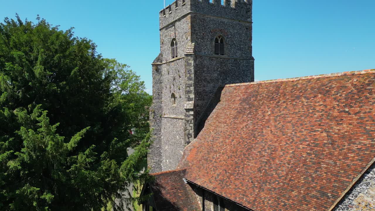 A rising boom-shot of St Mary's church, which ascends above the tower to unveil the union flag flying on the tower, and the village of Chartham