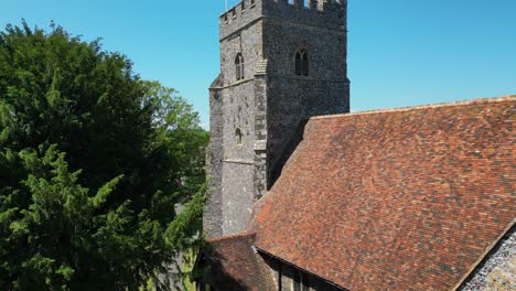 a rising boom-shot of st mary's church, which ascends above the tower to unveil the union flag flying on the tower, and the village of chartham