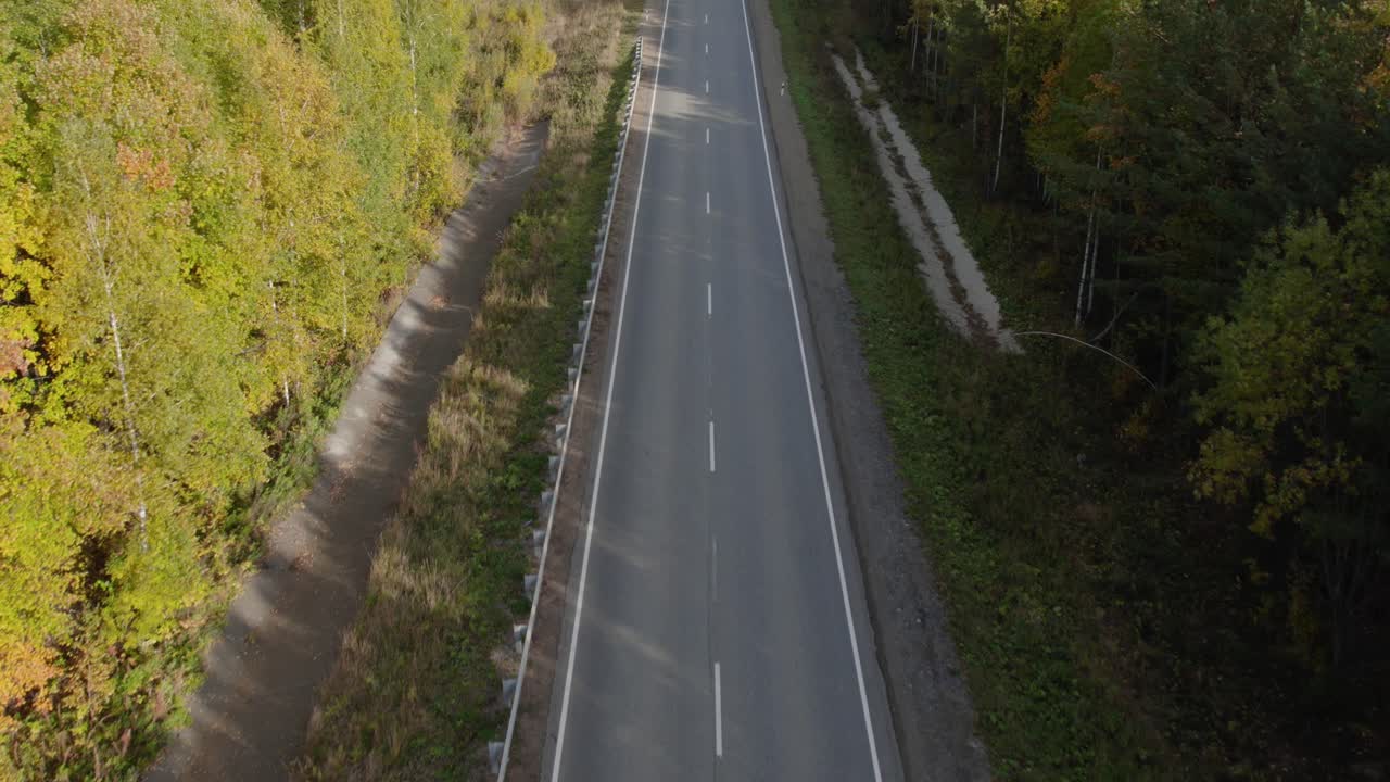 Dronebeelden van een rechte asfaltweg die door een kleurrijk herfstbos snijdt in het Oeralgebergte, Rusland, zonder verkeer, rustig wildernislandschap