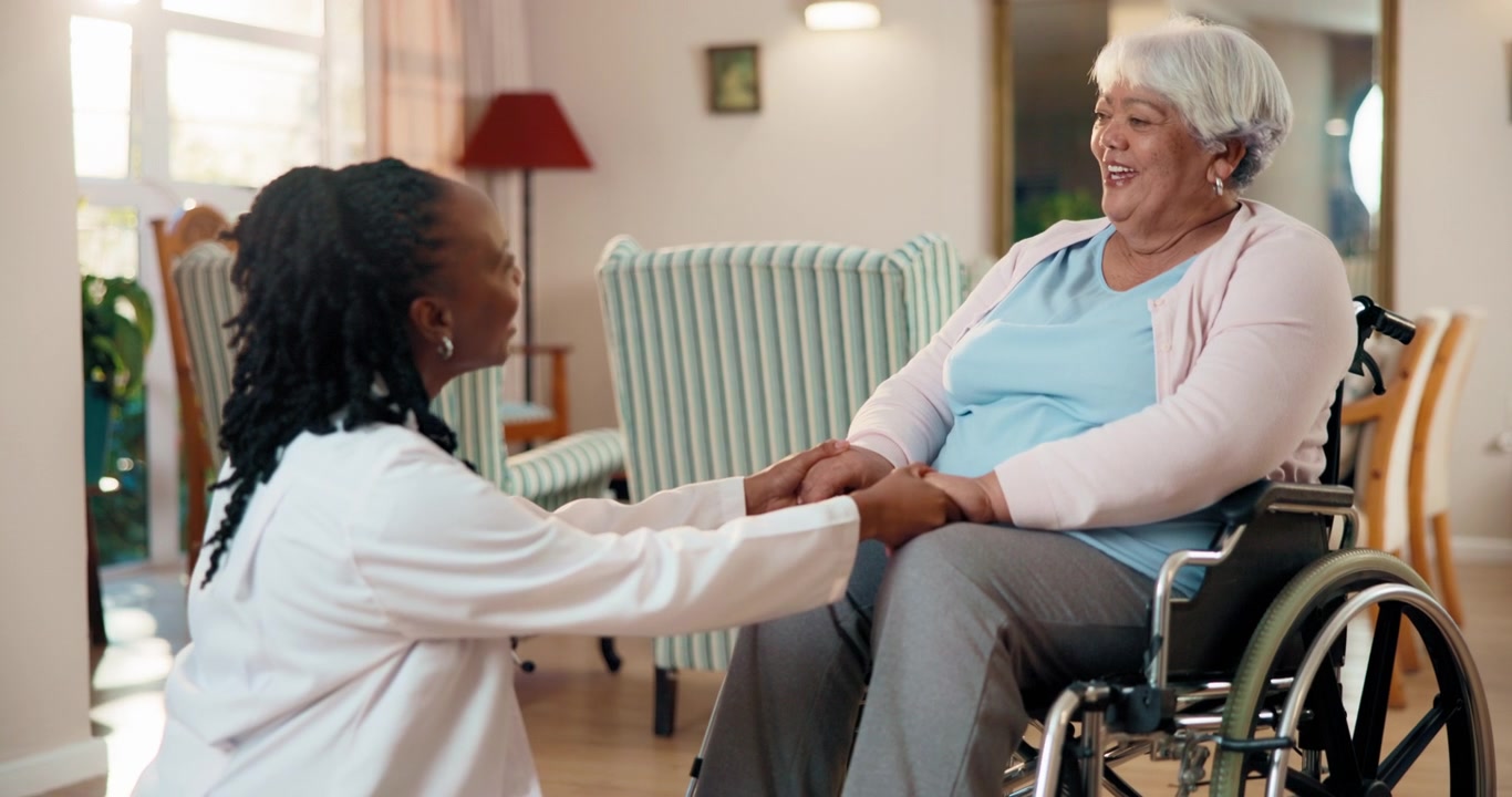 Doctor Holding Hands with Senior Woman in Wheelchair