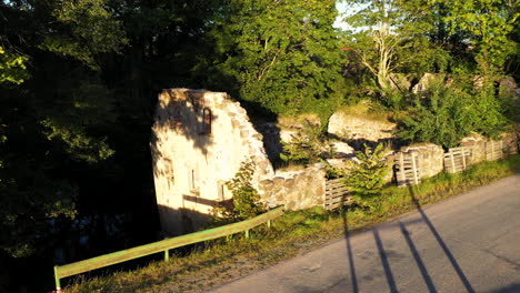 remains on antique stone building on roadside, aerial drone fly forward view