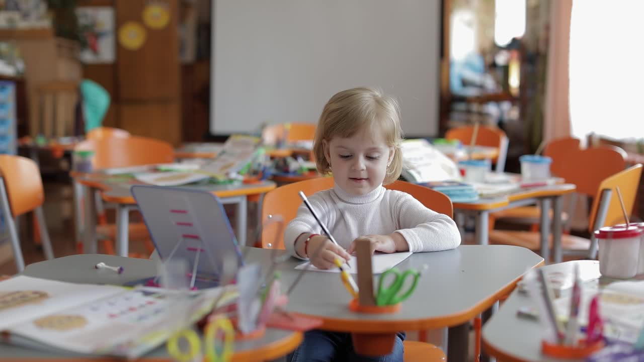 Girl drawing at the table in classroom. Education. Child sitting at a desk