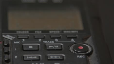 Close-up-of-finger-pressing-record-on-a-small-voice-recorder