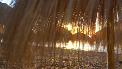 Amanecer-Marbella-Playa-Gimbal-Suave-Movimiento-A-Través-De-Sombrillas-De-Paja-4k