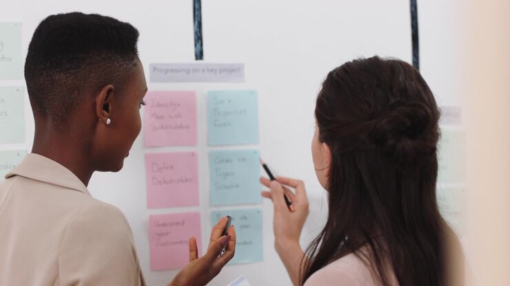 Two Businesswomen Collaborating on a Project Plan Using Sticky Notes
