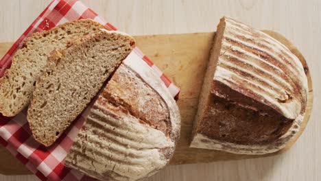 Video-of-loaf-of-bread-on-chopping-board-on-a-wooden-surface