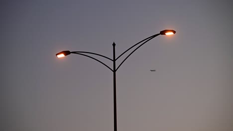 un avión que pasa detrás de una farola durante la puesta de sol en los eau