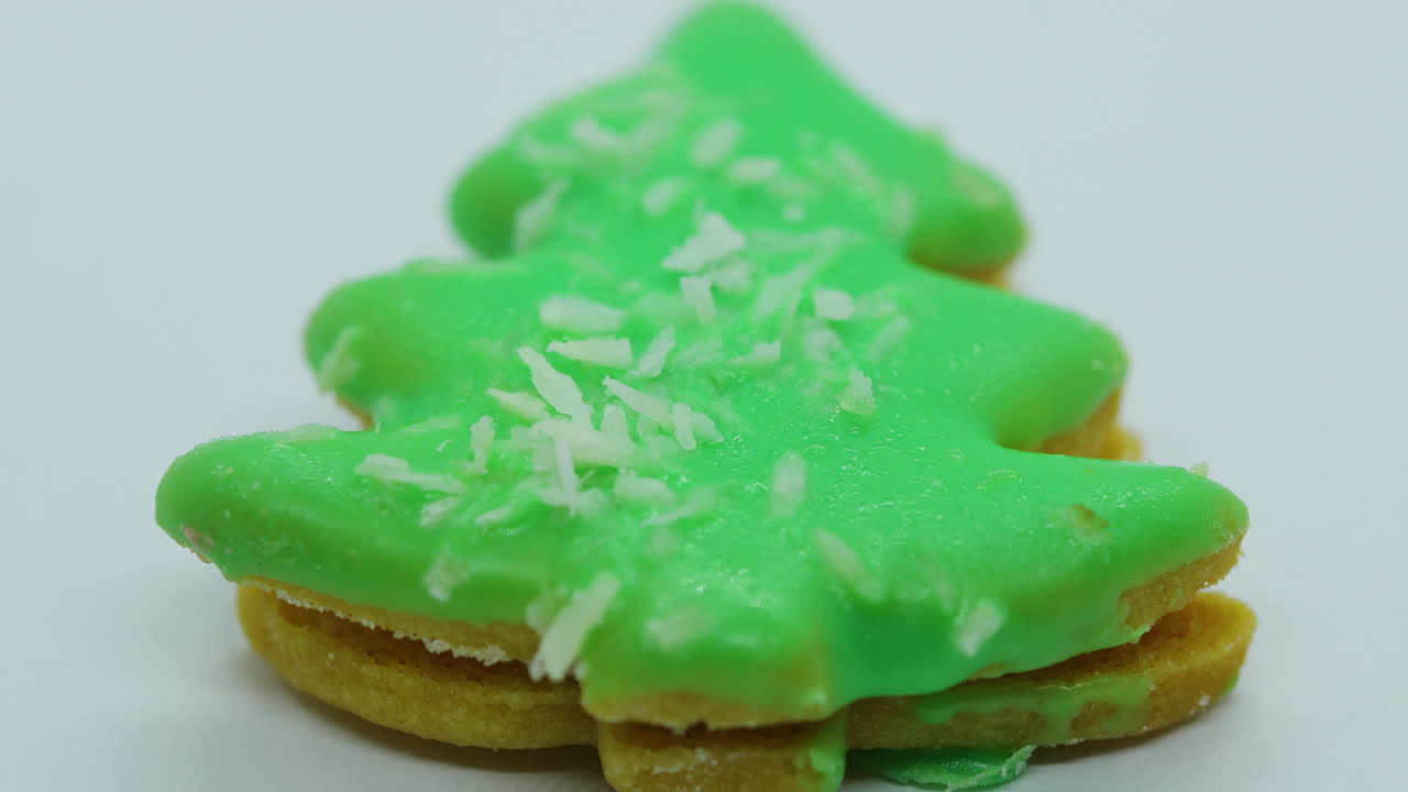 Close-up macro zoom in view of christmas cookies in the form of green Christmas tree with coconut on white background in slow motion capture
