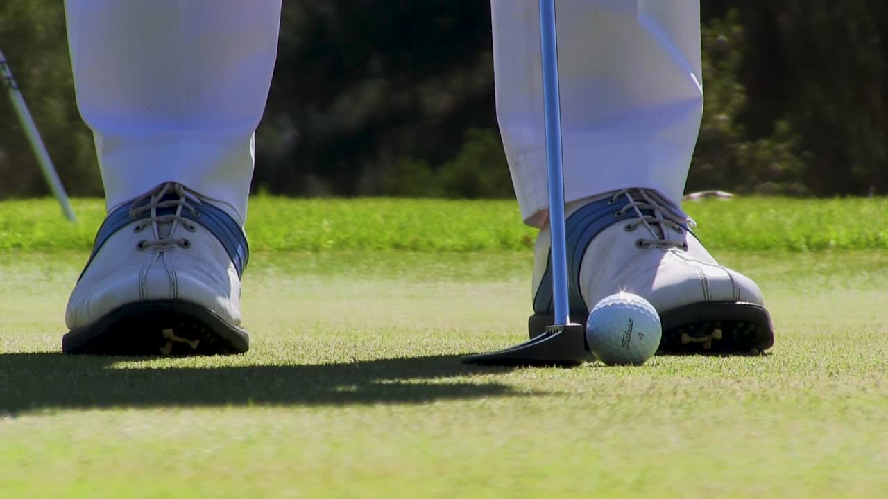 골퍼의 신발과 녹색 상단에 공을 치는 골프 클럽의 닫습니다