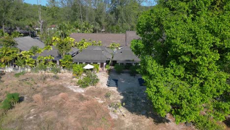 Magic-aerial-view-flight-drone-of-a-secluded-beach-resort-nestled-within-a-vibrant-green-forest,-showcasing-a-peaceful-holiday-destination