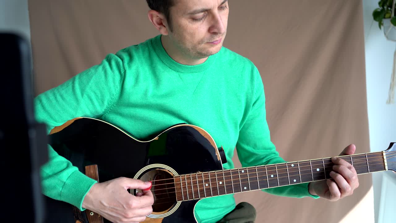 músico sonriente con video de grabación de guitarra en el teléfono inteligente