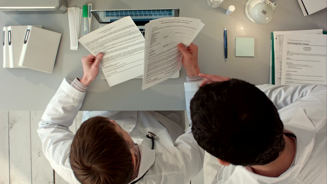 Doctor signing a medical report in his office. Top view