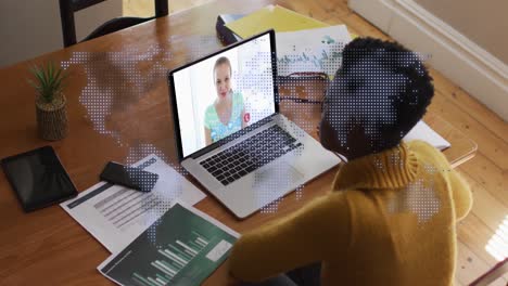Animation-of-world-map-over-african-american-woman-having-a-video-call-on-laptop-at-home