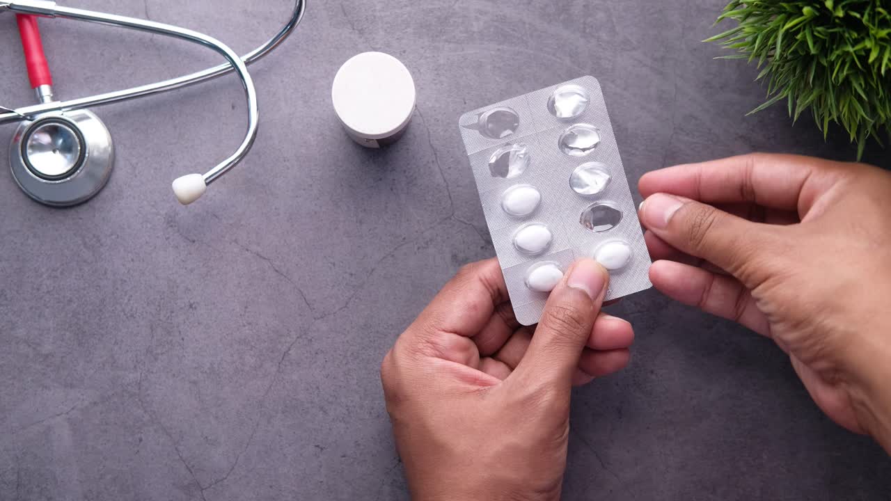 스테토스코프와 컨테이너를 배경으로 약을 복용하는 사람.