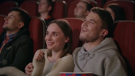 guy embracing girl while watching movie in cinema. love couple enjoy movie