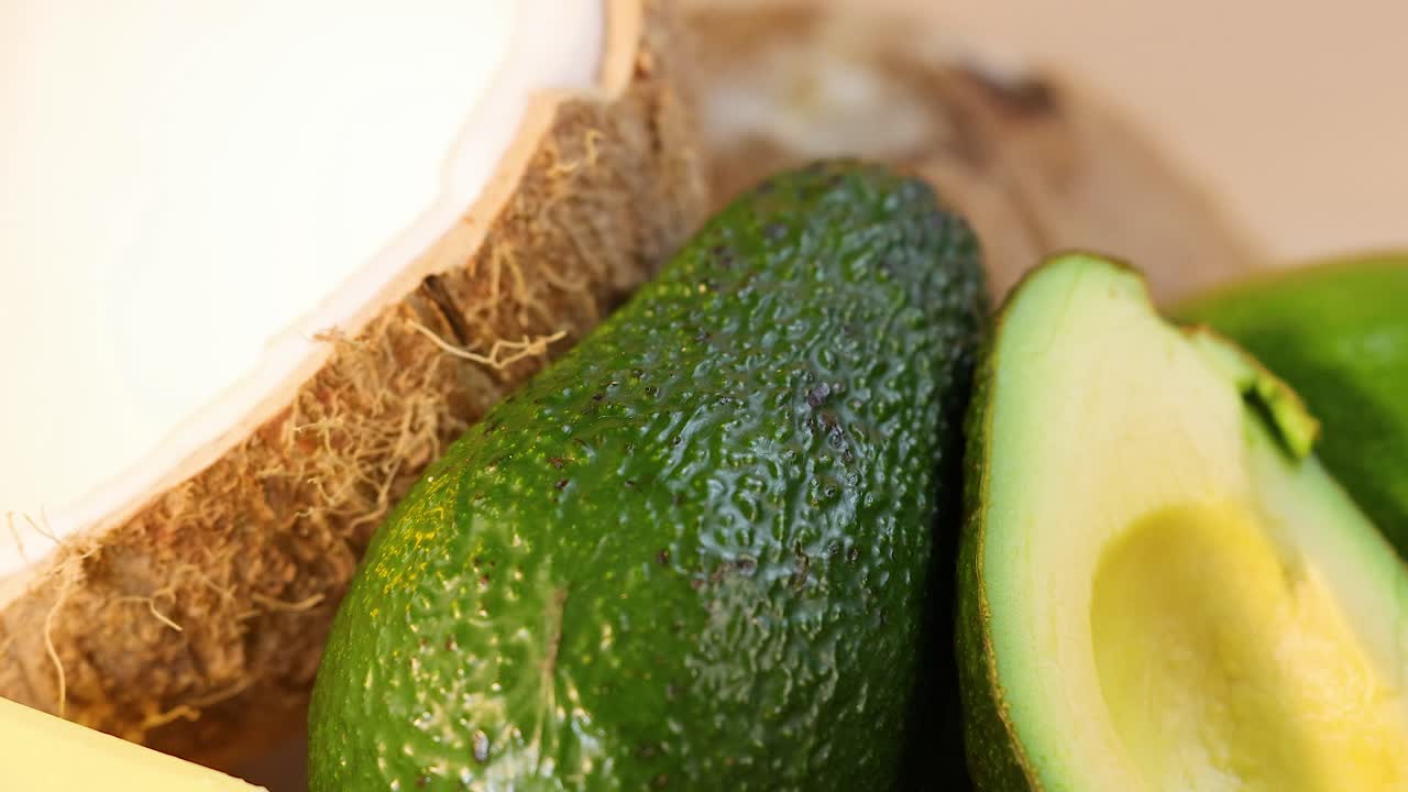 A vibrant arrangement of avocados, coconuts, oils, seeds, and olives in bright lighting