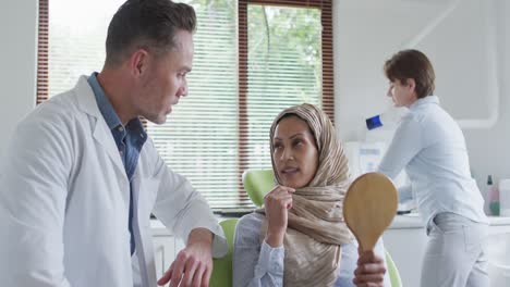 Caucasian-male-dentist-talking-with-female-patient-at-modern-dental-clinic