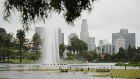 Eine-Totalaufnahme-Des-Echo-Park-Lake-Im-Regen-Mit-Der-Skyline-Der-Innenstadt-Von-La-Im-Hintergrund