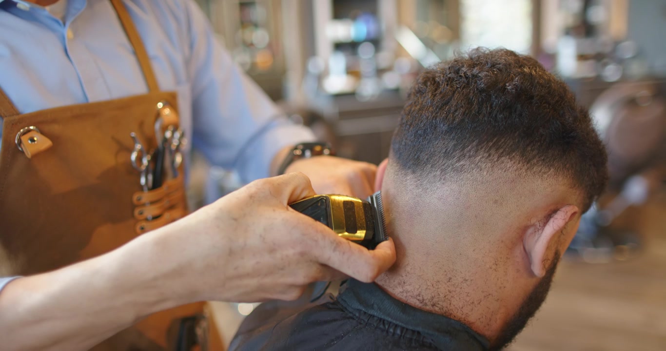 Barbeiro afro-americano e cliente na barbearia, barbeiro sentindo a nuca e usando máquina para finalizar o degradê